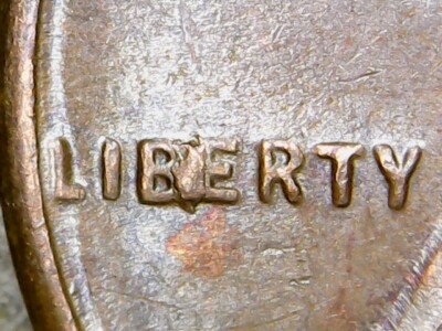 1954 wheat penny BIE die break error showing raised I-shaped chip between B and E in the word LIBERTY on the obverse